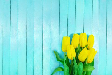 Mavi ahşap tahtalarda sarı laleler. Tatil, 8 Mart, Uluslararası Kadınlar Günü. Boşluğu kopyala