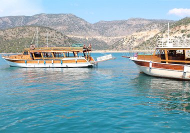 Parlak güneşli yaz aylarında mavi denizde yüzen turist teknesi. Yan görüş. Yatı, dağları, mavi suları olan bir manzara. Deniz kavramı, seyahat