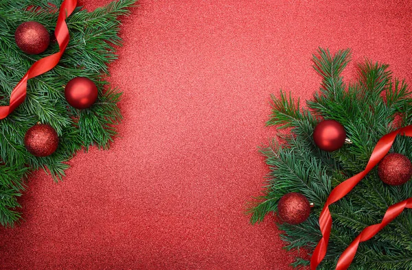 Shiny red balls and ribbons on fir branches on glitter background with place for text. Christmas, New Year. Copy space
