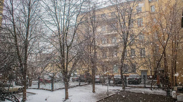 The beginning of winter and snowfall in the city courtyard.
