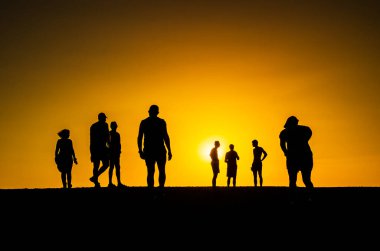 Group of people in silhouette walking towards the falling sun