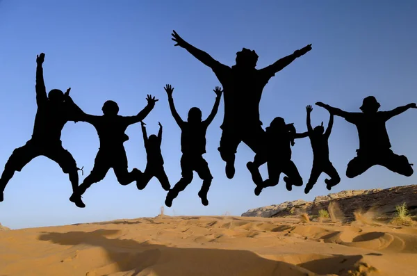 Silhouttes of people jumping in the desert of wadi rum