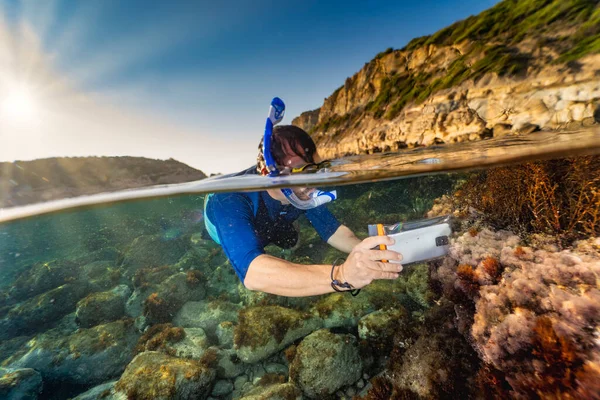 Snorkeller taking pictures underwater with a cellular phone in a waterproof bag
