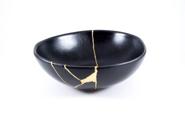 İzole edilmiş siyah Japon kintsugi kasesi, altın çatlaklarıyla restore edilmiş antika çömlek. Geleneksel altın düzeltme yöntemi.