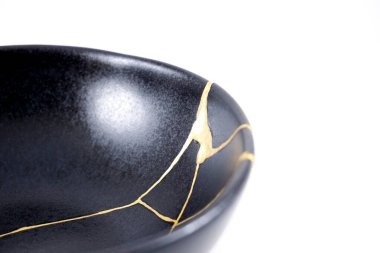 İzole edilmiş siyah Japon kintsugi kasesi, altın çatlaklarıyla restore edilmiş antika çömlek. Geleneksel altın düzeltme yöntemi.