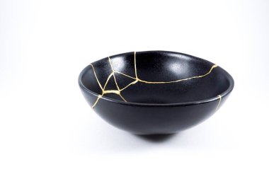 İzole edilmiş siyah Japon kintsugi kasesi, altın çatlaklarıyla restore edilmiş antika çömlek. Geleneksel altın düzeltme yöntemi.