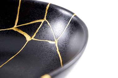 İzole edilmiş siyah Japon kintsugi kasesi, altın çatlaklarıyla restore edilmiş antika çömlek. Geleneksel altın düzeltme yöntemi.