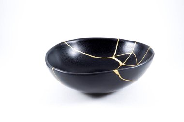 İzole edilmiş siyah Japon kintsugi kasesi, altın çatlaklarıyla restore edilmiş antika çömlek. Geleneksel altın düzeltme yöntemi.