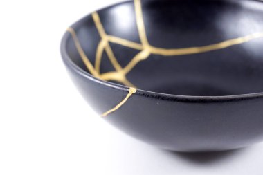 İzole edilmiş siyah Japon kintsugi kasesi, altın çatlaklarıyla restore edilmiş antika çömlek. Geleneksel altın düzeltme yöntemi.