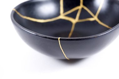 İzole edilmiş siyah Japon kintsugi kasesi, altın çatlaklarıyla restore edilmiş antika çömlek. Geleneksel altın düzeltme yöntemi.