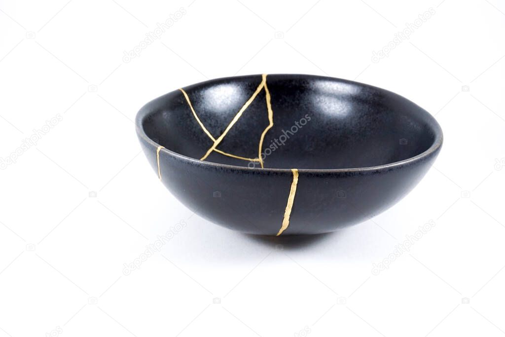 Gold cracks Kintsugi, broken black repaired bowl, Japanese technique.