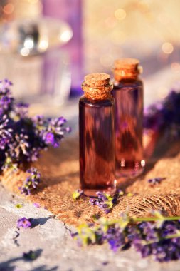 Bokeh arka planında lavanta yağı ve lavanta çiçekleri.