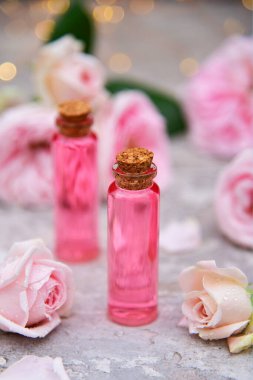 Gül çiçekleri ve bokeh arka planında bir şişe gül yağı.