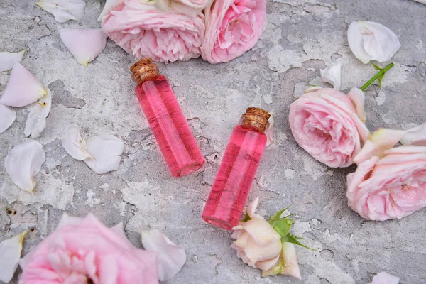Eine Flasche Rosenöl Auf Einem Hintergrund Aus Rosenblüten Und Bokeh — Stockfoto