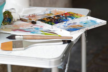 Yağlı boyalı sanat paleti ve masadaki fırçalar.