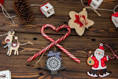 Çam dalları arasında tahta bir arka planda Noel ağacı oyuncakları ve şekerler.