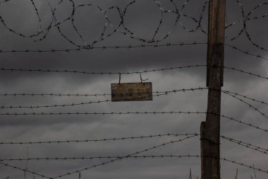 Yasak bir bölgeyi çevreleyen işaretleri olan eski dikenli teller..