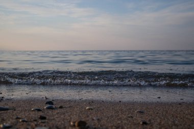 Dalgalar deniz kenarında, berrak mavi su