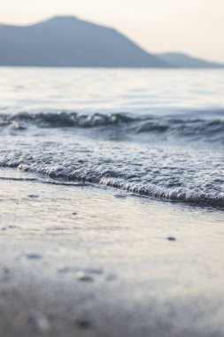 Dalgalar deniz kenarında, berrak mavi su