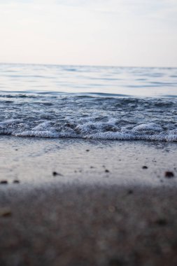 Dalgaların ve kabarcıkların yakın çekimi deniz kenarında, berrak mavi su