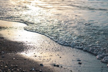 Dalgalar deniz kenarında, berrak mavi su