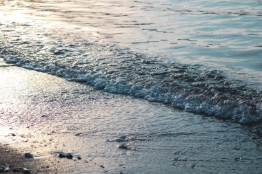 Dalgalar deniz kenarında, berrak mavi su