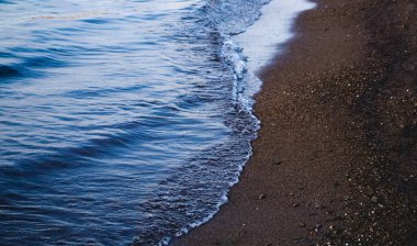 Dalgalar deniz kenarında, berrak mavi su