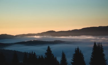 Bulutların üstünde görünüm, arka planda dağlar, yükselen güneş zamanı