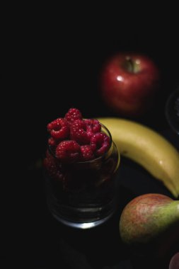 Siyah arka planda farklı meyveler, böğürtlen, muz, elma, ahududu, kızılcık