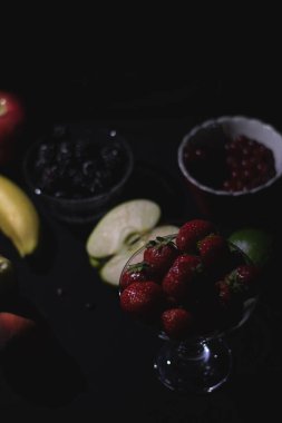 Siyah arka planda farklı meyveler, böğürtlen, muz, elma, ahududu, kızılcık