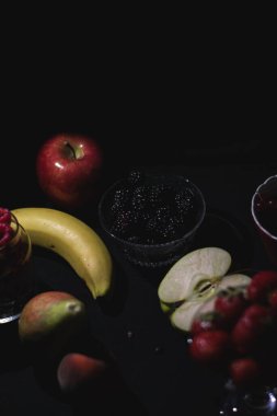 Siyah arka planda farklı meyveler, böğürtlen, muz, elma, ahududu, kızılcık