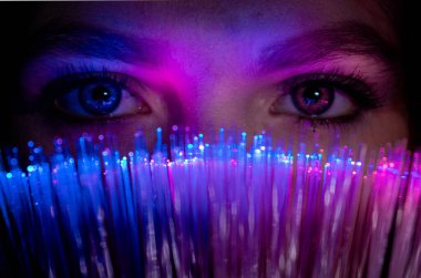 Female looks through futuristic teal coloured bokeh millennial, woman girl looking at camera with advanced fiber optic technology, Christmas