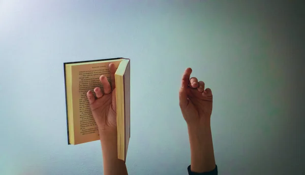 Female hand, one holding a book, hands in the air, art concept
