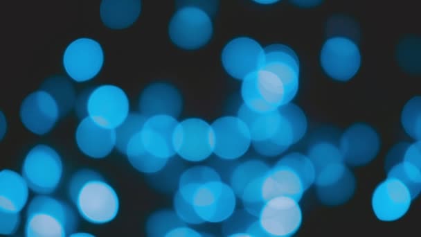 Blaue, verschwommene Weihnachtslichter flackern im Dunkeln. abstrakte festliche Bokeh Hintergrund — Stockvideo