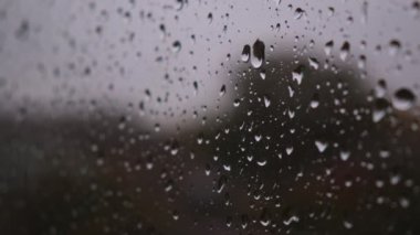 Şiddetli sağanak yağmur damlacıkları pencerenin camından aşağı süzülüyor.