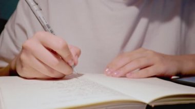 Hassas elleri olan bayan öğrenci günlük gazetede yazmak için siyah kalem kullanıyor.
