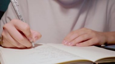 Yumuşak elli genç öğrenci günlük günlüğe düşüncelerini yazmak için siyah kalem kullanıyor.