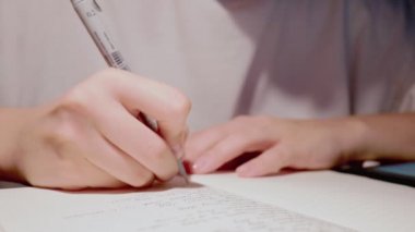 Genç kadın, günlük günlüğün beyaz kağıt sayfasına el yazısı yazıyor.