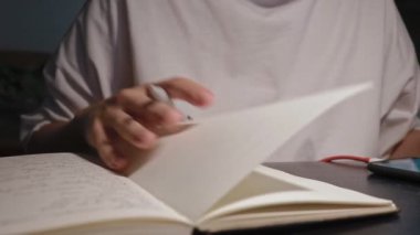 Genç öğrenci, günlük gazetenin sayfalarını çevirip beyaz kağıda yazmaya hazırlanıyor.