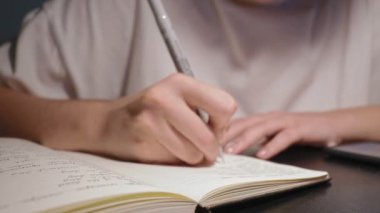 Ödev yapan genç bir öğrenci beyaz kağıda siyah kalemle not defterine yazmış.