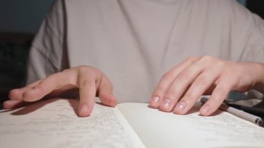 Genç öğrenci beyaz kağıt defterinin sayfalarını çeviriyor günlük günlük günlük yavaş çekim