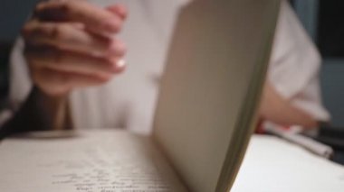 Genç öğrenci ödev defterinin beyaz sayfalarını yavaş çekimde çeviriyor.