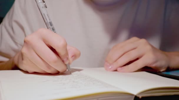 Junge Studentin macht Hausaufgaben in weißem Papier-Notizbuch in Nahaufnahme-Zeitlupe — Stockvideo