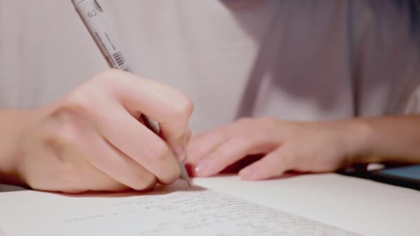 若い女性が手書きのテキストを毎日の日記の白い紙のページに書き — ストック動画