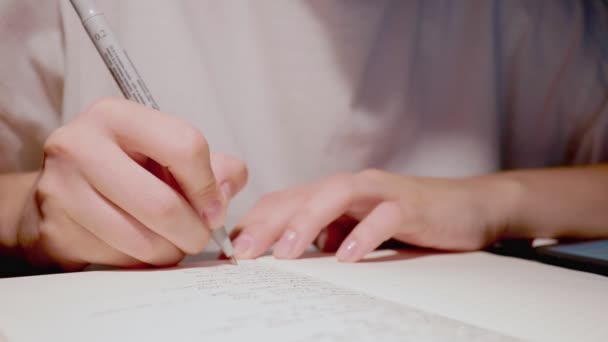Jonge vrouwelijke hand met behulp van zwarte pen om gedachten op papier schrijven op witte pagina — Stockvideo