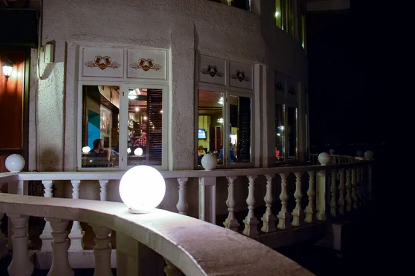 Akşam geç saatlerde panoramik pencerelerde yemek yiyen tanınmayan insanlarla dolu şık bir restoran balkon terası..