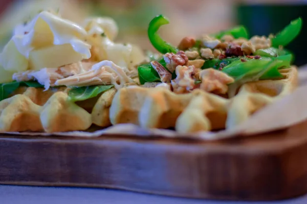 Tahtadaki yeşil sebzeli, fındıklı ve peynirli sağlıklı Belçika waffle 'ının detaylarını kapat.