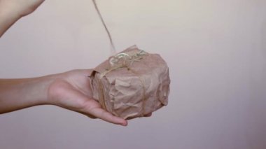 Kadın elleri, yeniden kullanılabilir çevre dostu sıfır atık el yapımı kağıt ambalajlı organik geri dönüşümlü malzemelerle ev yapımı ev yapımı Noel hediyelerini açıyor.