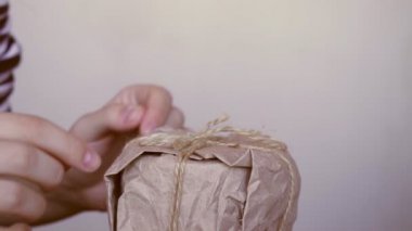 Kadın elleri, yeniden kullanılabilir çevre dostu sıfır atık el yapımı kağıt ambalajlı organik geri dönüşümlü malzemelerle ev yapımı ev yapımı Noel hediyelerini açıyor.