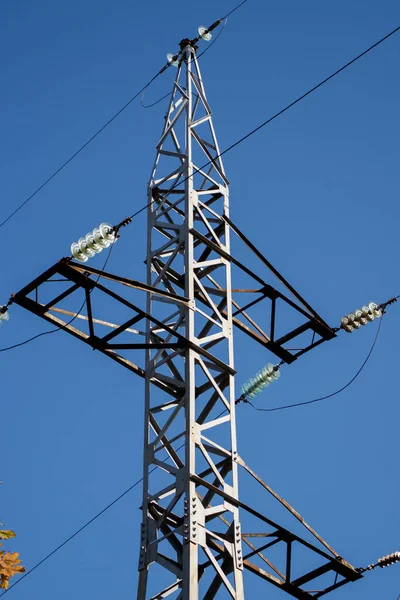 Temiz mavi gökyüzü arkaplanına karşı kabloları olan elektrik ağı çelik kulesi.